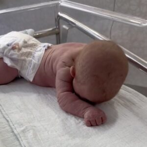 Newborn baby crawls across the hospital cot